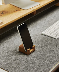 Smartphonehalter aus massivem Eichenholz mit Korkelement, der ein Smartphone aufrecht und griffbereit auf dem Schreibtisch hält.