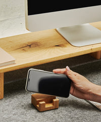 Smartphonehalter aus massivem Eichenholz mit Korkelement, der ein Smartphone aufrecht und griffbereit auf dem Schreibtisch hält.