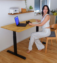 Weibliche Person arbeitet an Höhenverstellbarem Tisch Eiche Natur. Im Hintergrund Regale Schubi, passend zu der NaturTischplatte