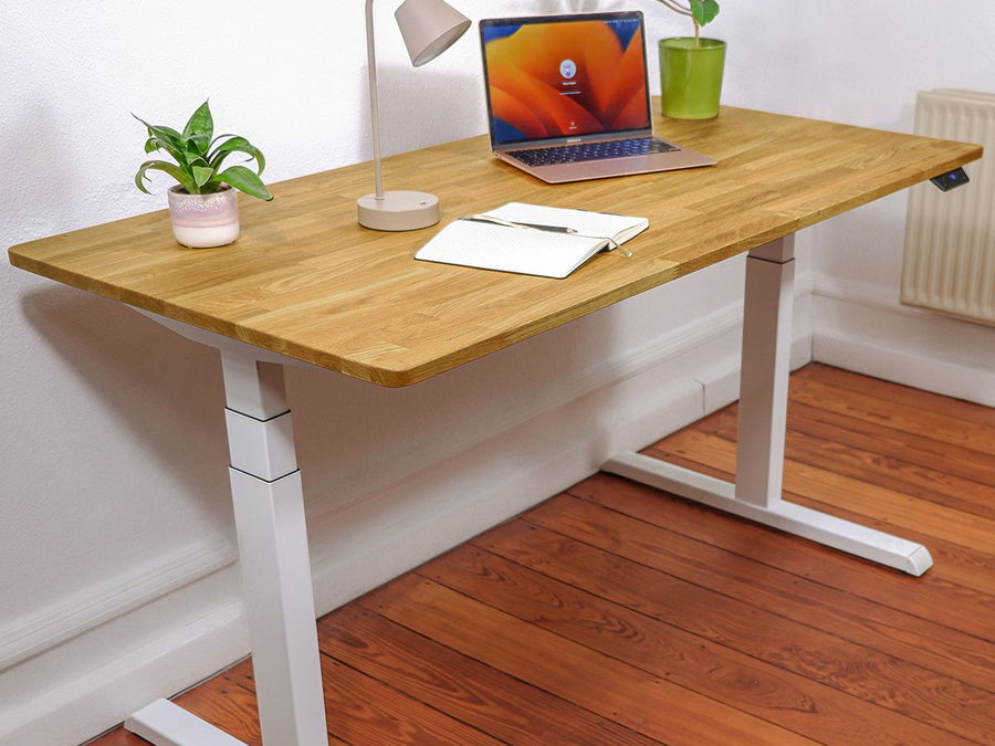 Höhenverstellbarer Schreibtisch - Eiche Natur White in einem Raum stehend. Eingerichteter, ergonomischer Home-Office Arbeitsplatz mit Fokus auf Eleganz und natürliche Holzoptik. Schrägansicht.