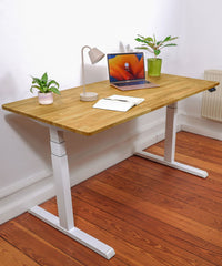 Höhenverstellbarer Schreibtisch - Eiche Natur White in einem Raum stehend. Eingerichteter, ergonomischer Home-Office Arbeitsplatz mit Fokus auf Eleganz und natürliche Holzoptik. Schrägansicht.