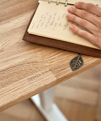 Höhenverstellbarer Schreibtisch mit Tischplatte aus naturbelassenem Eichenholz und weißem Gestell.