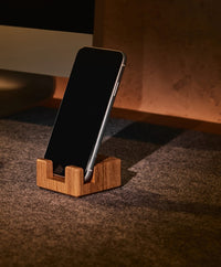 Smartphonehalter aus massivem Eichenholz mit Korkelement, der ein Smartphone aufrecht und griffbereit auf dem Schreibtisch hält.