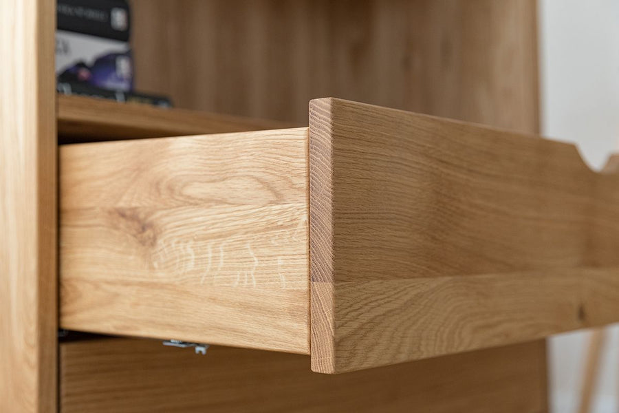 Bücherregal aus Massivholz Eiche mit einer geöffneten Schublade, mit Fokus auf die gut verarbeitete Maserung der Regalklappe aus Eiche